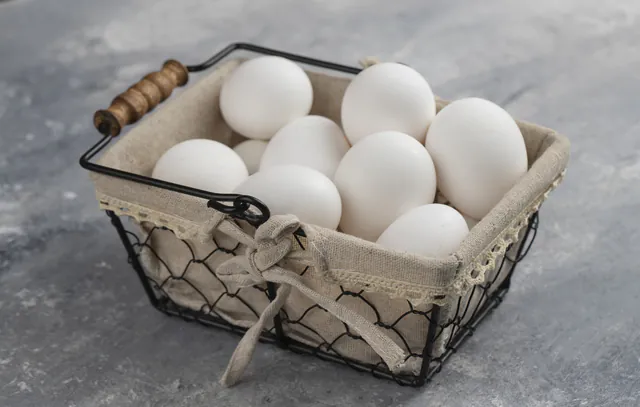 Basket full of fresh white chicken eggs on a marble background