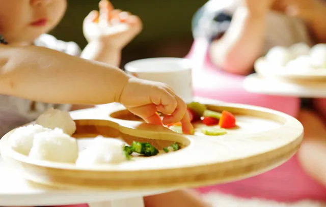 Little child eating meal with bare hands,close up