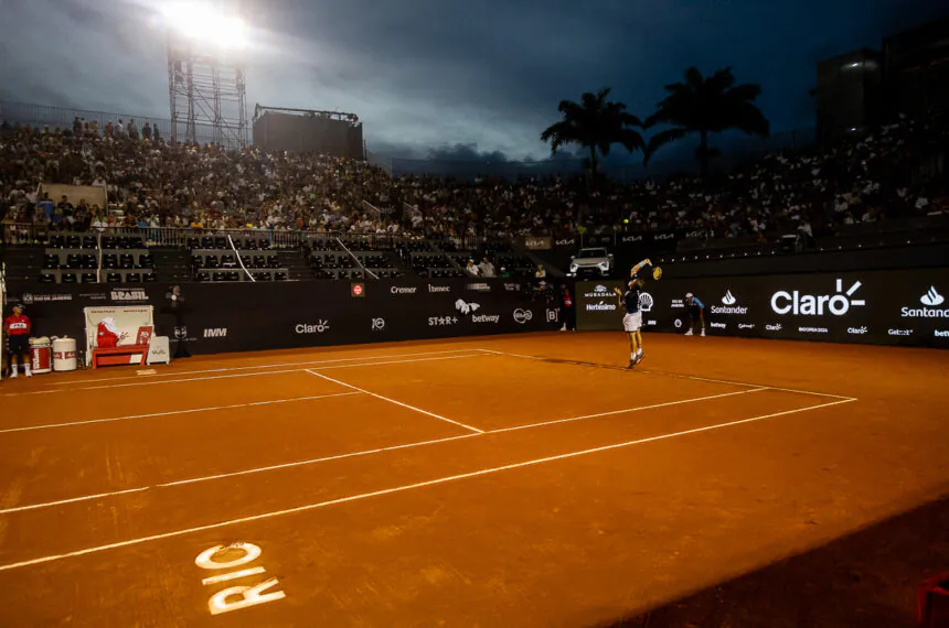 Felipe Meligeni Alves sacando na quadra central do Rio Open ao anoitecer