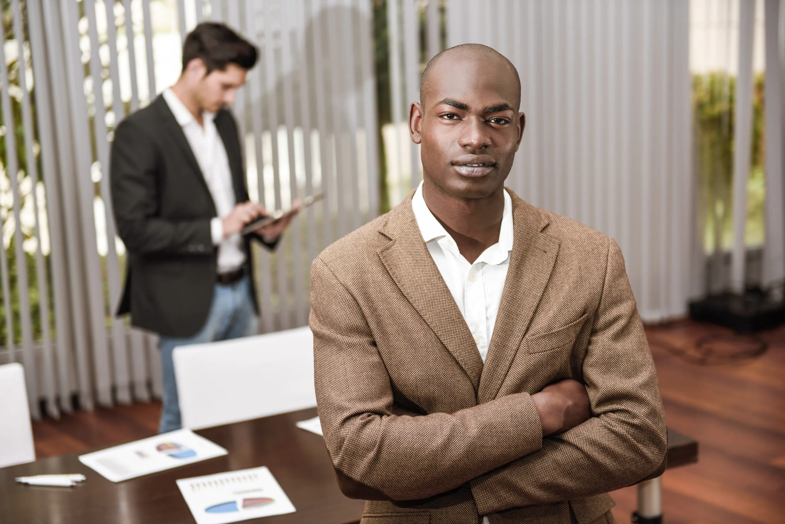 Cheerful young African man in formalwear keeping arms crossed